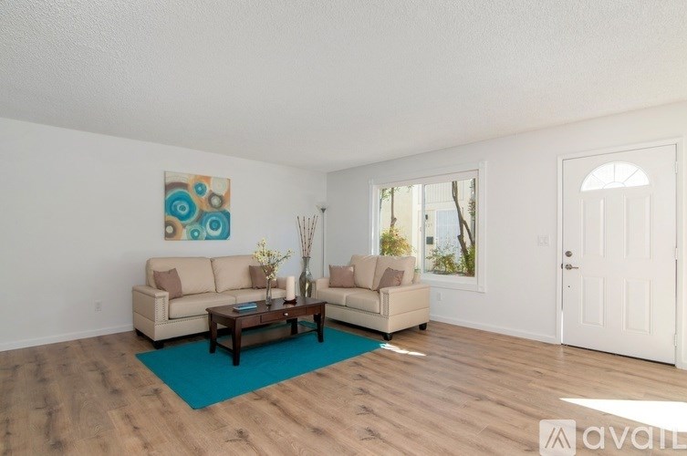 A living room with a couch, a coffee table, and a painting on the wall.