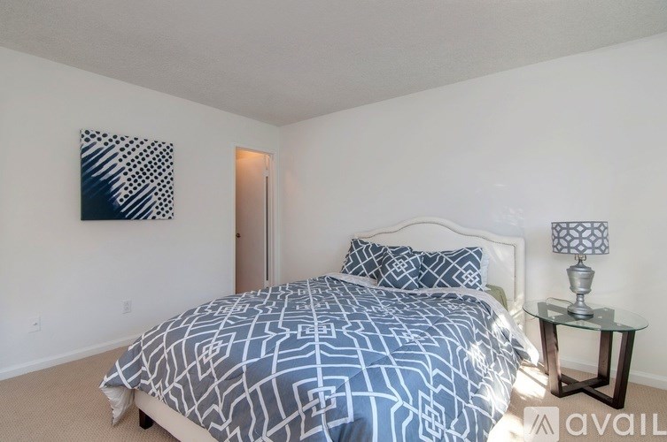 A bedroom with a bed, nightstand, and lamp.