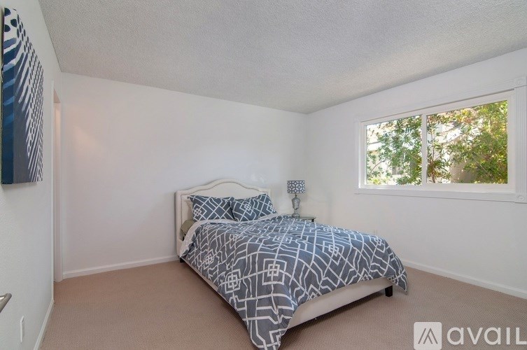 A bedroom with a bed, nightstand, and window.