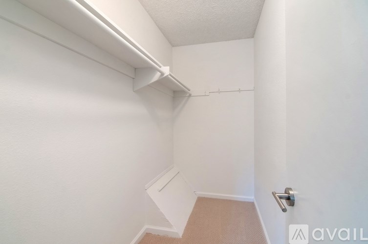 A small, empty room with a carpeted floor and a door on the right side.