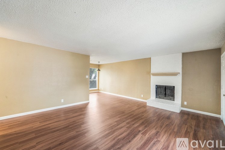 A spacious room with a fireplace and wooden flooring.