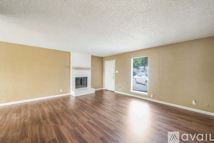 A spacious room with a fireplace and wooden flooring.