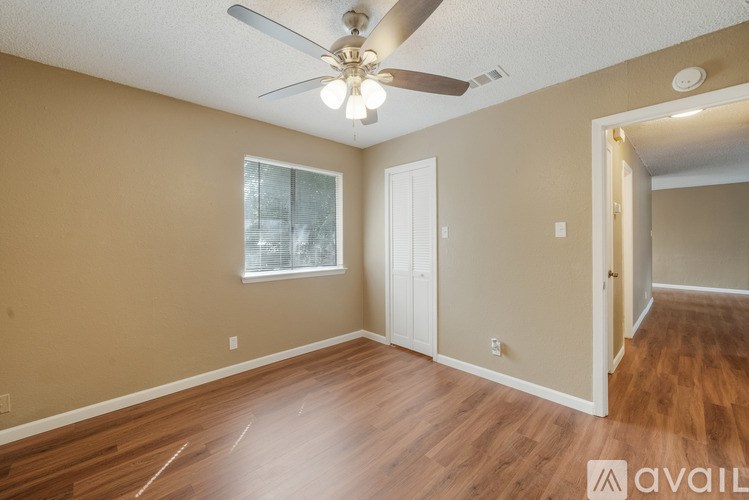 A room with a ceiling fan and wooden flooring.