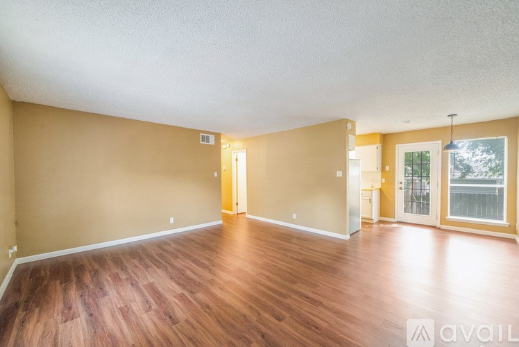 A room with wooden flooring and a door leading to a balcony.
