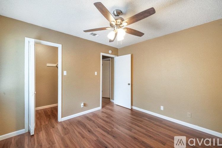 A room with a ceiling fan and wooden flooring.