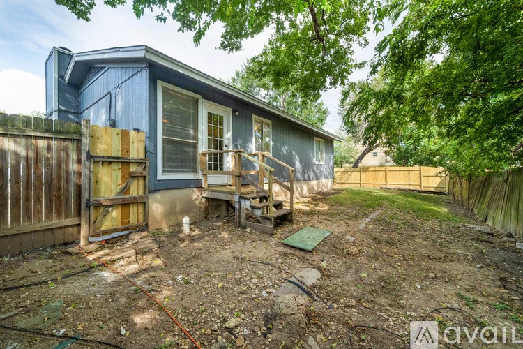 A blue house with a wooden fence and trees in the background.