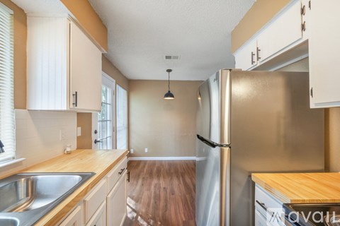 A kitchen with a stainless steel refrigerator and wooden countertops.