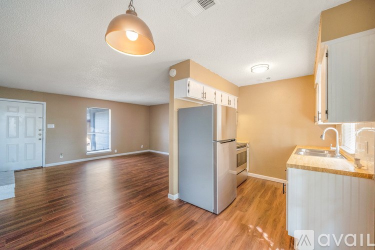 A kitchen area with a refrigerator, sink, and cabinets.