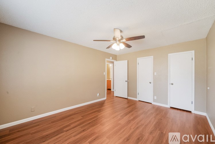 A room with a ceiling fan and wooden flooring.