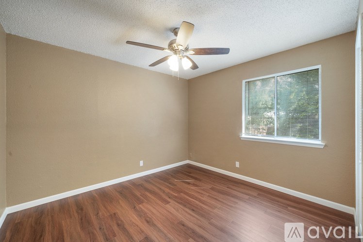 A room with a ceiling fan and a window with blinds.