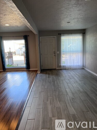 A room with wooden flooring and a door leading to a balcony.