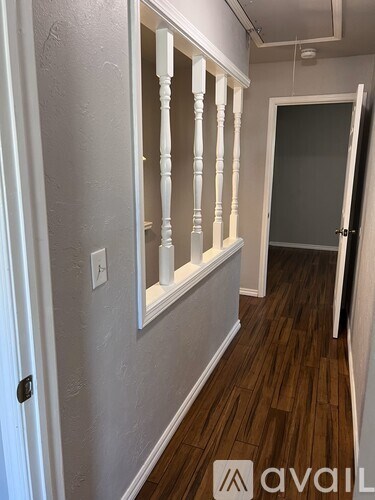 A hallway with wooden floors and white walls.