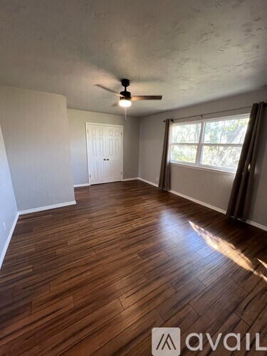 A room with wooden flooring and a ceiling fan.