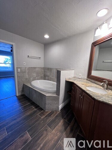 A bathroom with a tub, sink, and mirror.