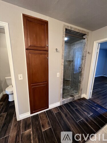 A wooden door in a room with a marble wall and wooden flooring.