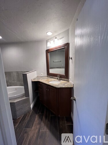 A bathroom with a tub, sink, and mirror.