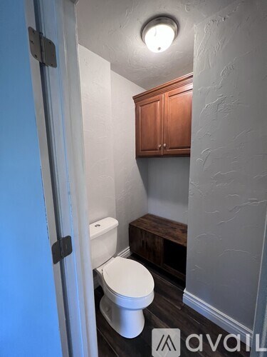A white toilet in a small bathroom with wooden cabinets.