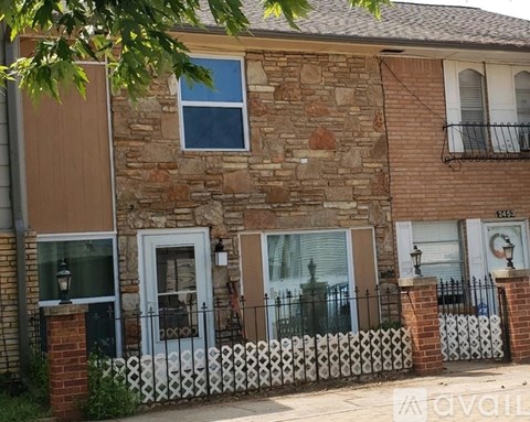 A stone and brick house with a white picket fence.