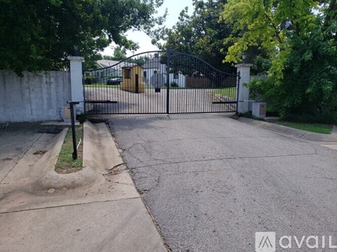 A black gate with a white pillar and a small house behind it.