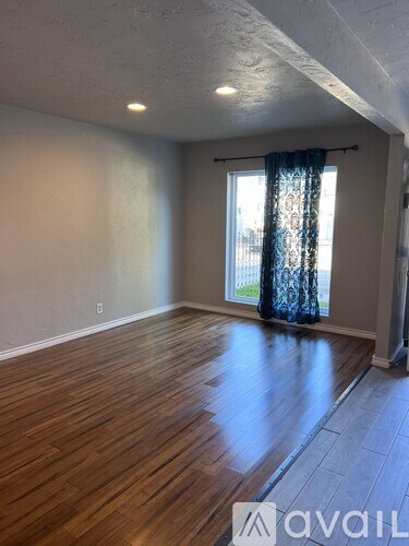 A room with wooden flooring and a window with curtains.