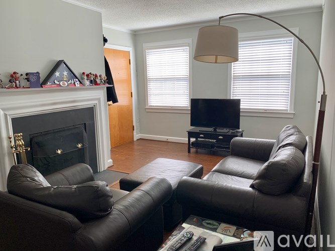 A living room with a fireplace, two leather chairs, and a coffee table.