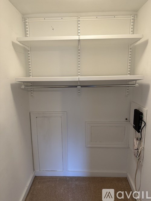 A white shelving unit with three shelves is mounted on a white wall.