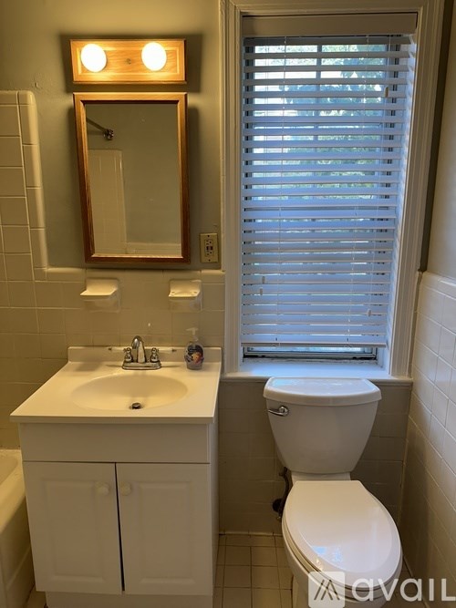 A white bathroom with a toilet, sink, and mirror.