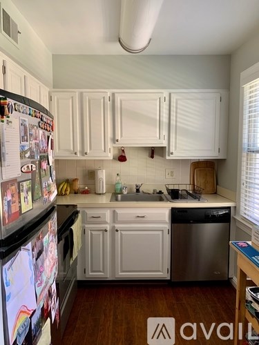 A kitchen with white cabinets and a fridge covered in magnets.
