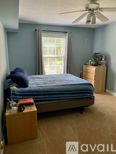 A bedroom with a bed, nightstand, and window.