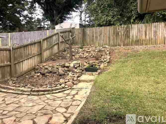 A backyard with a stone pathway and a wooden fence.