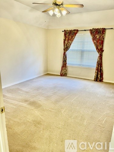 A room with a ceiling fan and a window with curtains.