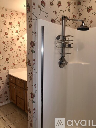 A white shower stall with a shower head and a rack.