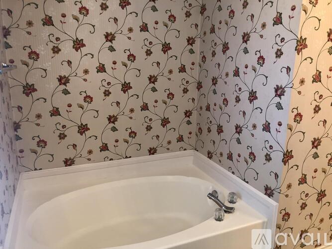 A white bathtub with a floral patterned shower curtain.