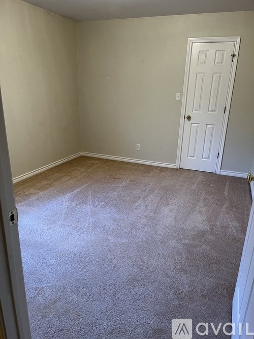 A room with a white door and carpeted floor.