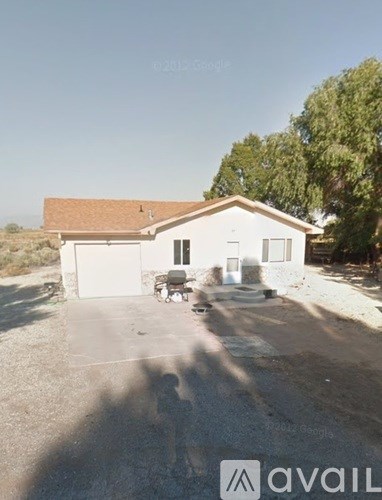 A white house with a brown roof and a driveway in front.