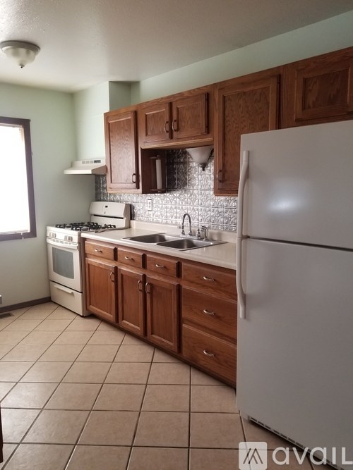 A kitchen with a white refrigerator, wooden cabinets, and a tiled floor.