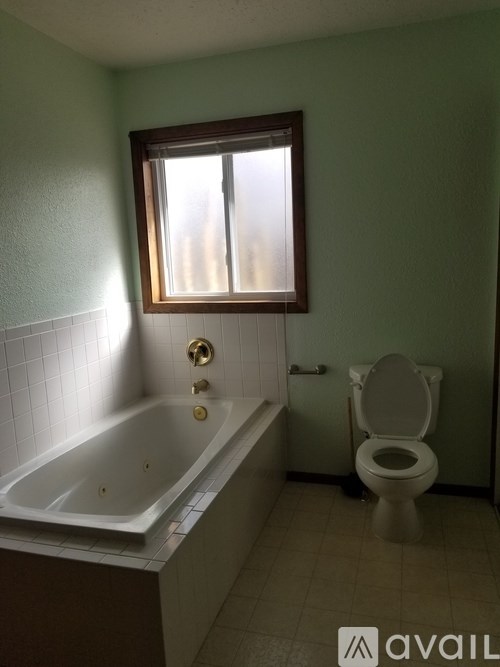 A bathroom with a toilet, tub, and window.