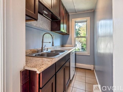 A kitchen with brown cabinets and a window.
