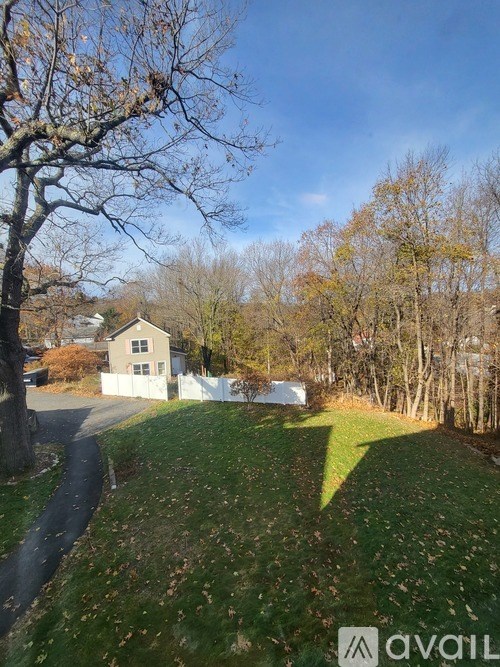 A house with a white fence is surrounded by trees and grass.