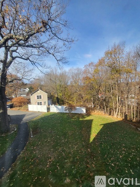 A house with a white fence is surrounded by trees and grass.
