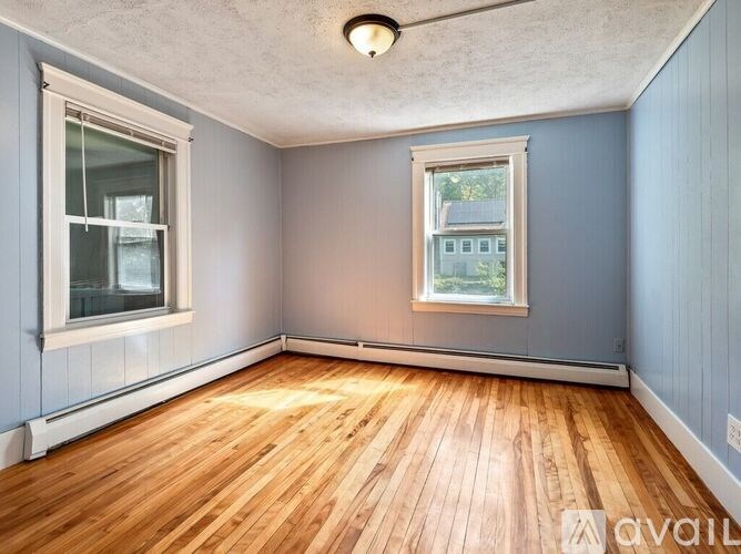 A room with wooden floors and two windows.