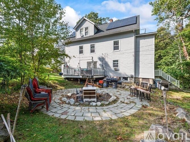 A house with a solar panel on the roof and a patio with chairs and a fire pit.
