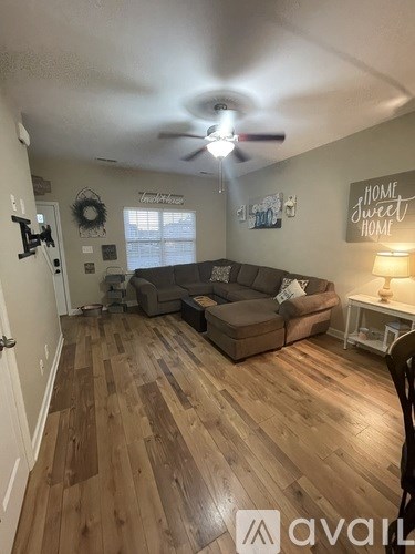 A living room with a brown couch and wooden floors.