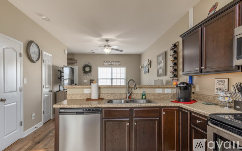 A kitchen with a stainless steel dishwasher and wooden cabinets.