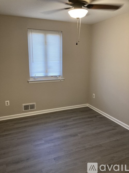 A room with a ceiling fan and a window with blinds.