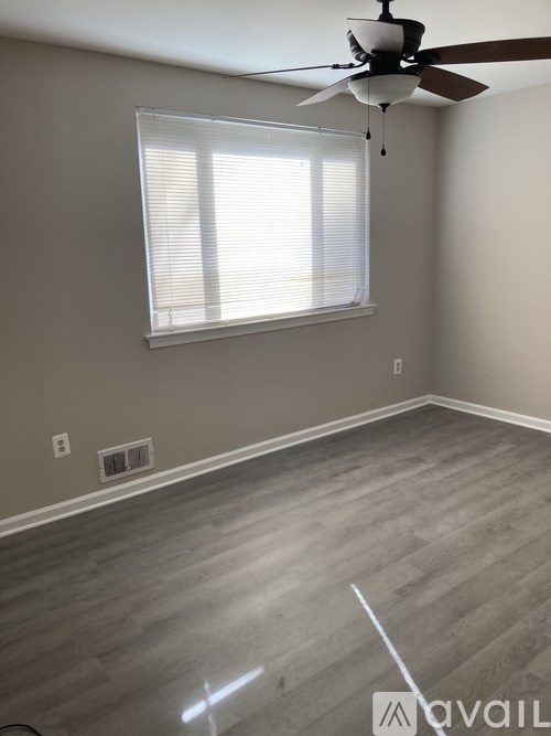 A room with a ceiling fan and a window with blinds.