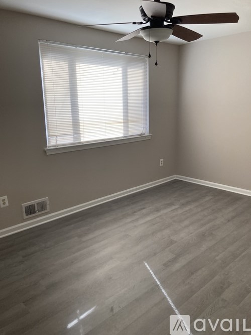 A room with a ceiling fan and a window with blinds.
