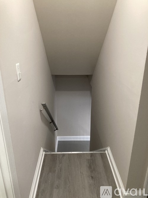 A hallway with a wooden floor and white walls.