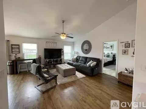 A living room with a black couch and a ceiling fan.