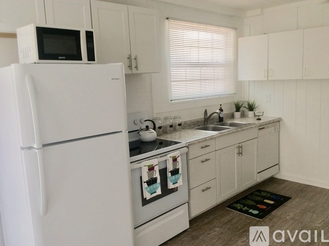 A white refrigerator is in a kitchen with white cabinets.